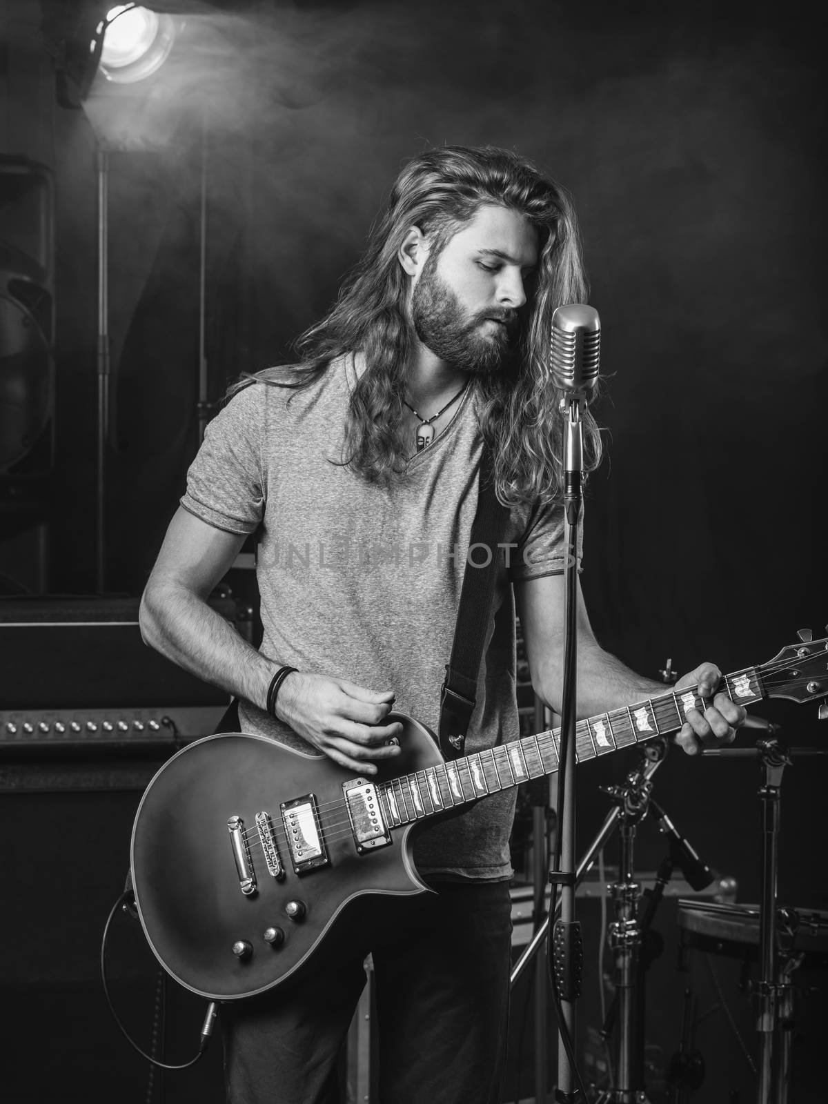 Photo of a young man playing electric guitar on stage.