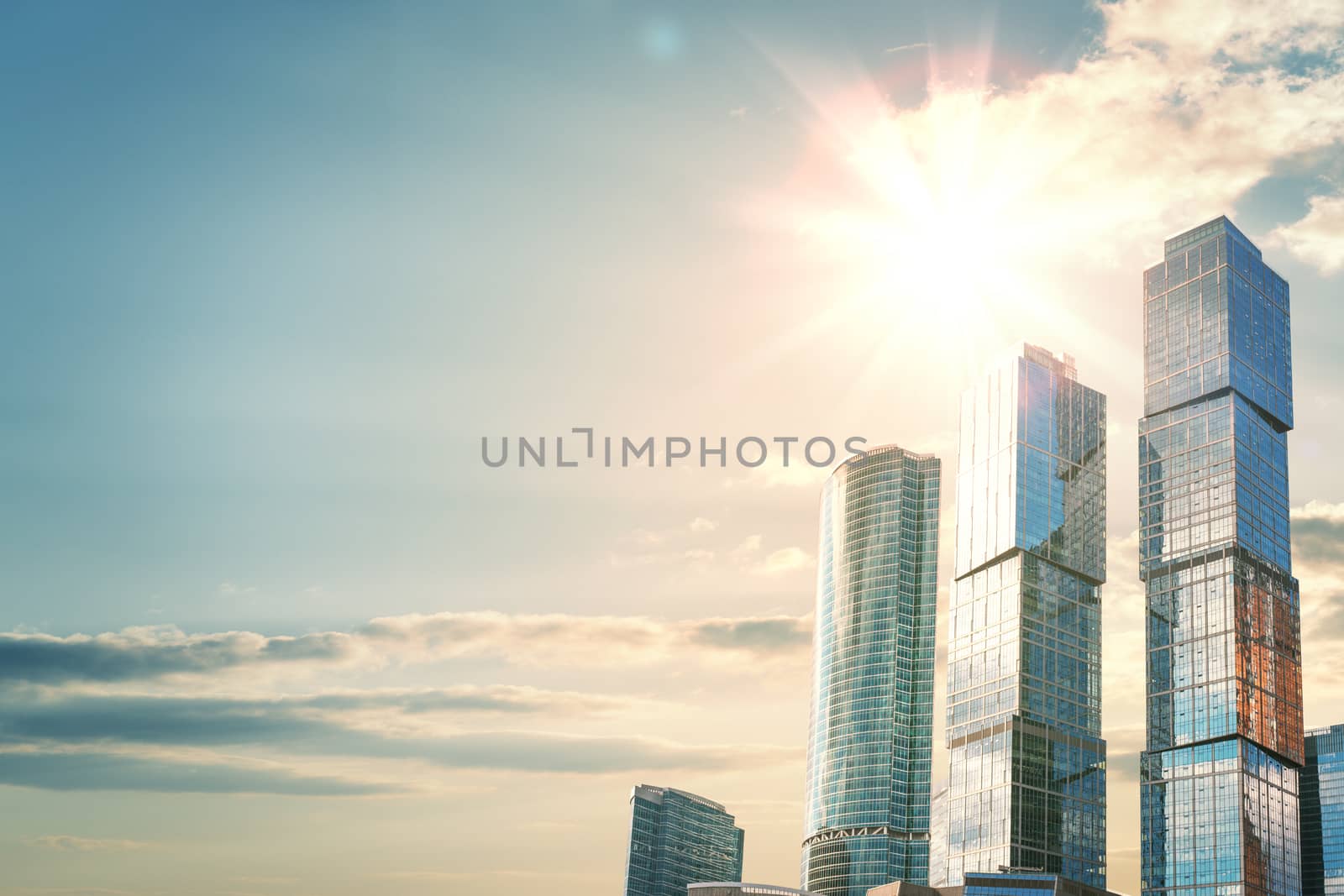 Several skyscrapers with glass facades against a beautiful sunrise. The concept of growth and success