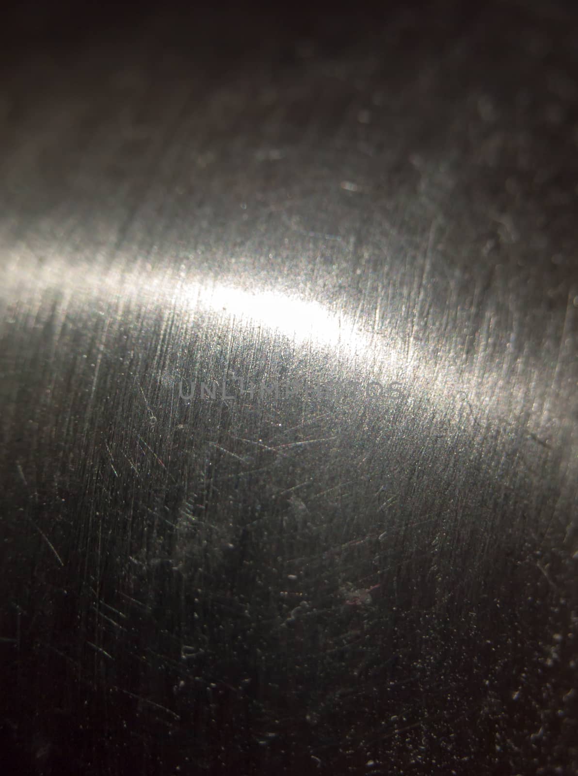 close up scratched metal surface with light across; UK