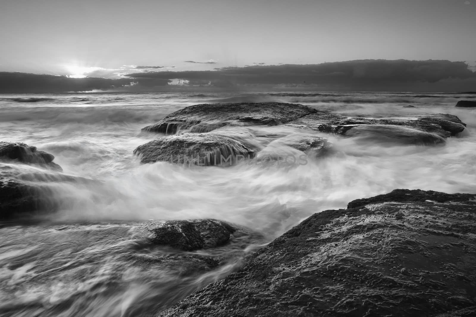 Rocky coastline with ocean surges and  whitewater flows.  Black and white.  Location  Bungan beach Australia