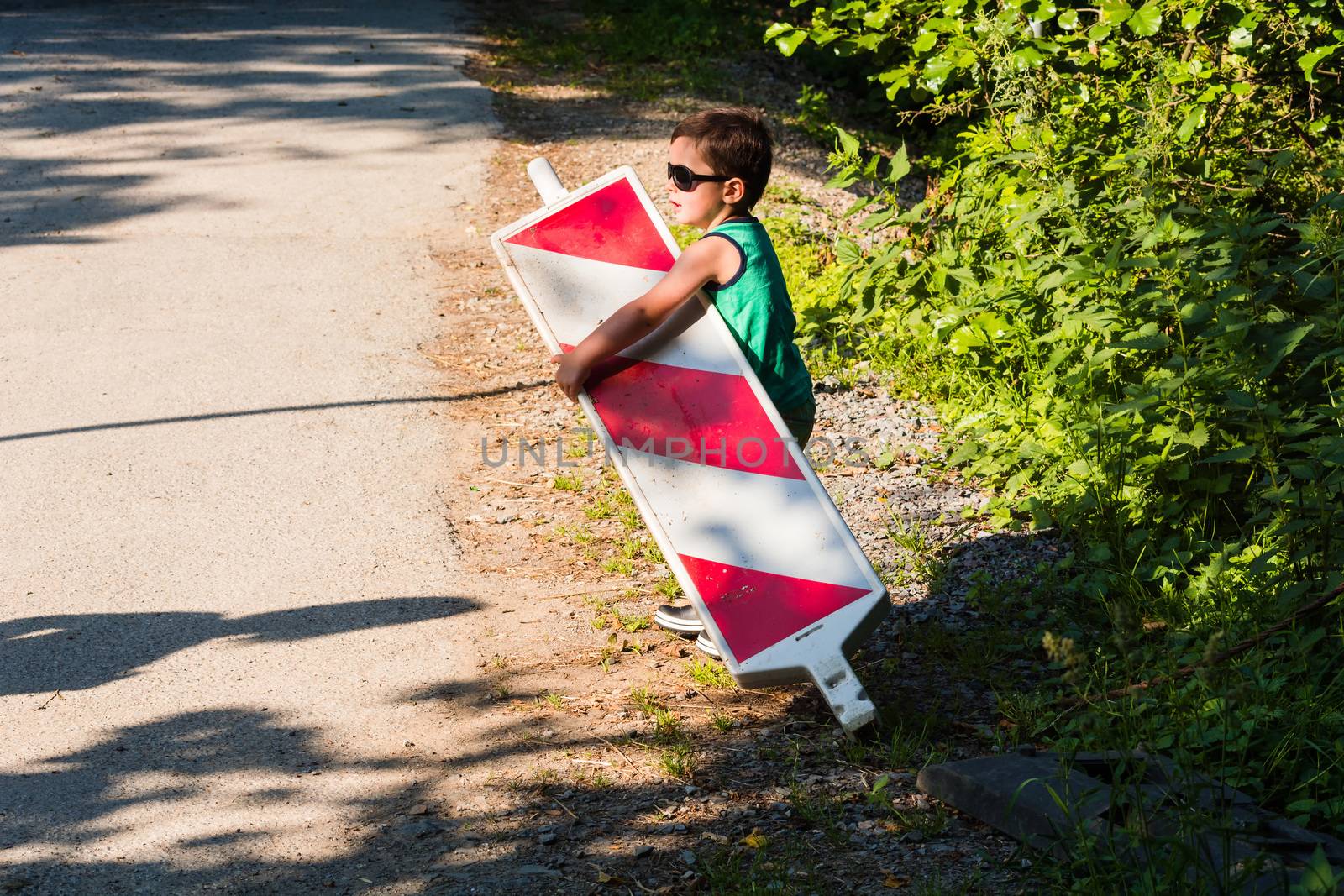 Little boy is carrying a construction site barrier across the street. To overcome difficulties