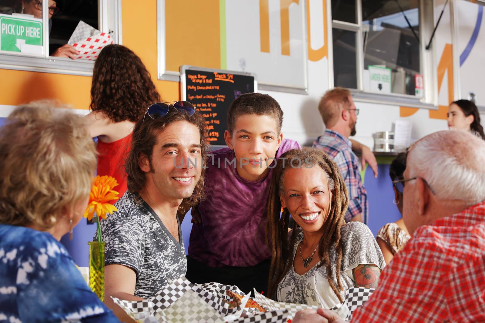 Diverse family of three with grandparents having lunch from a food truck