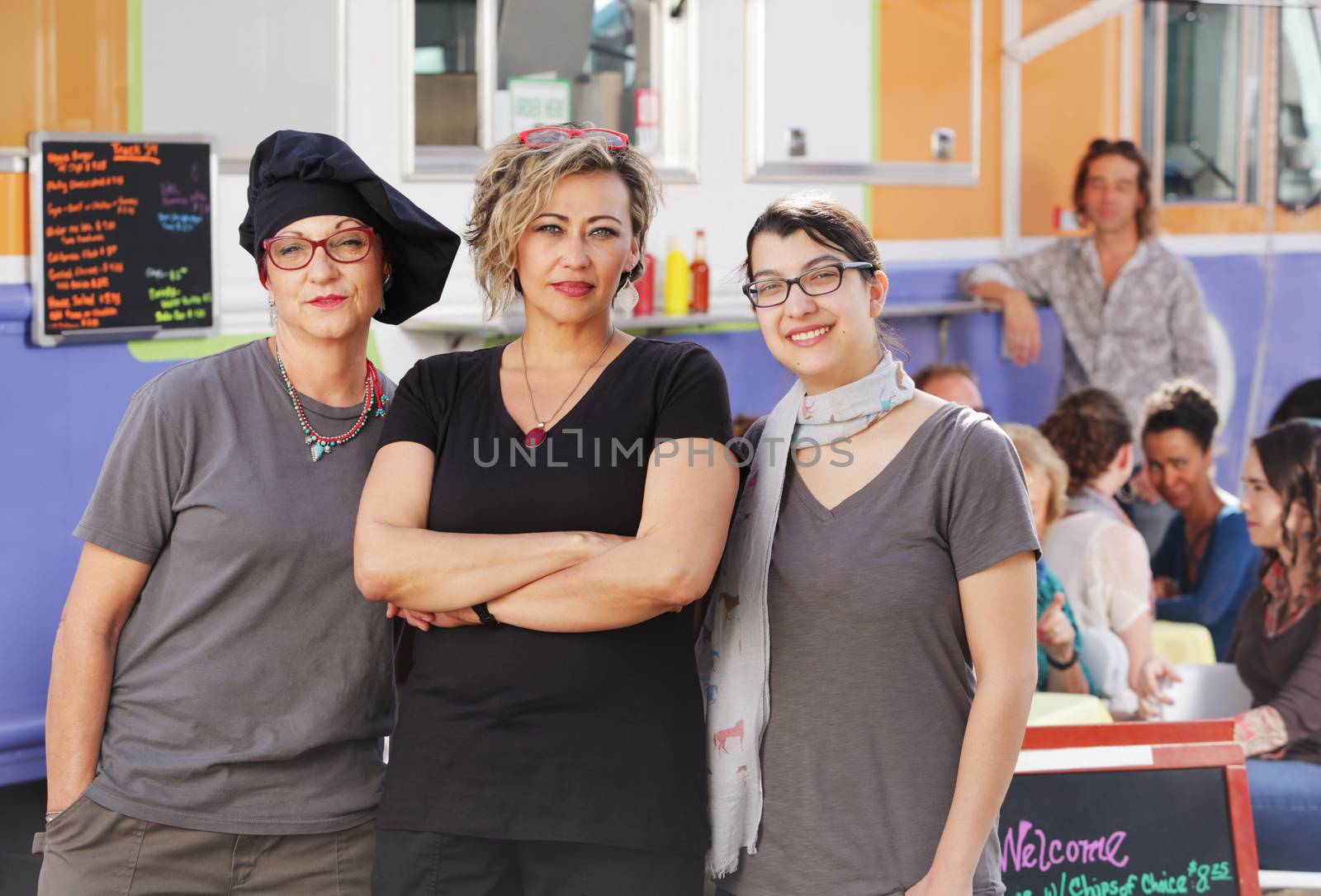 Three food workers posing in front of an outdoor food truck