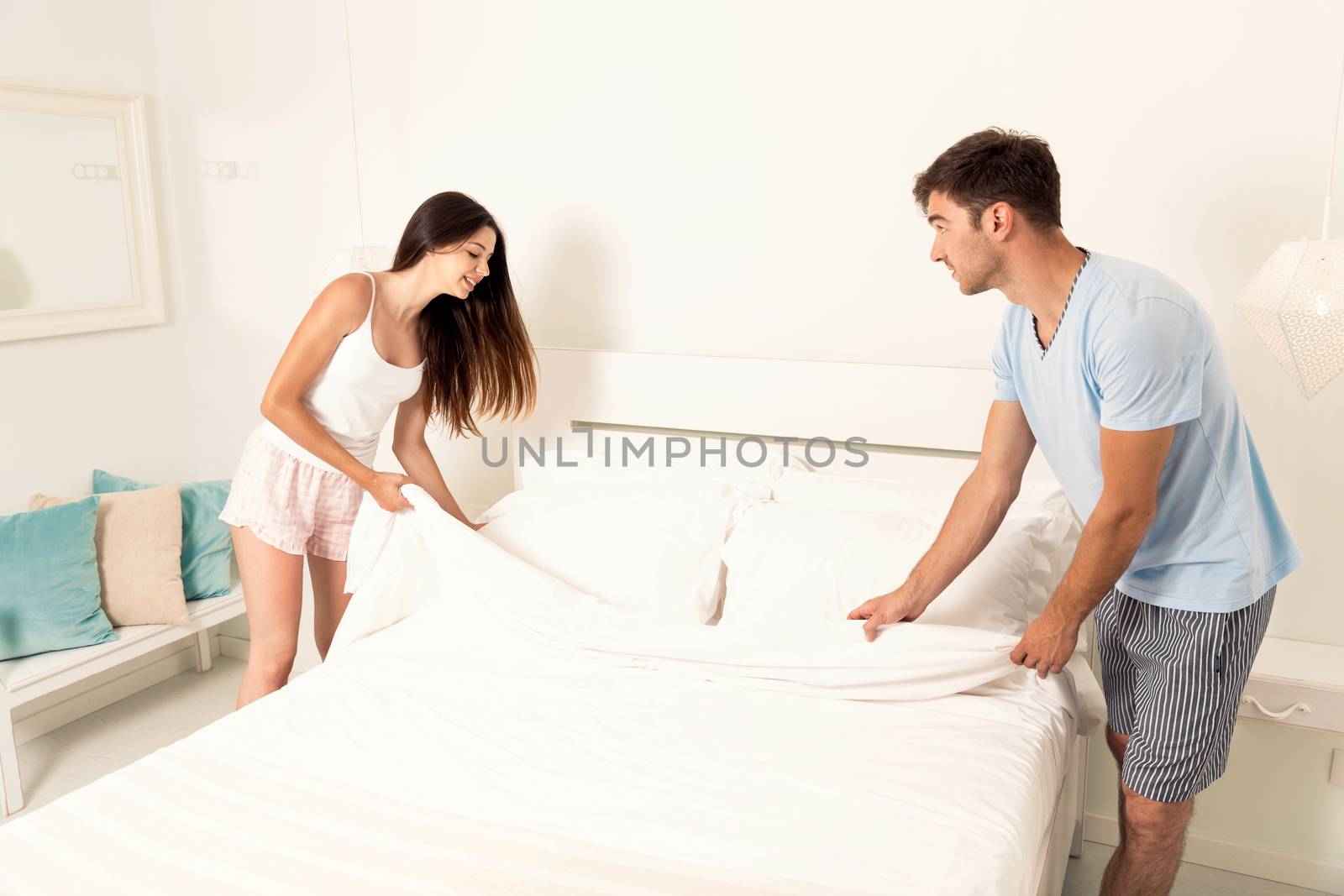 Young couple making the bed after waking up