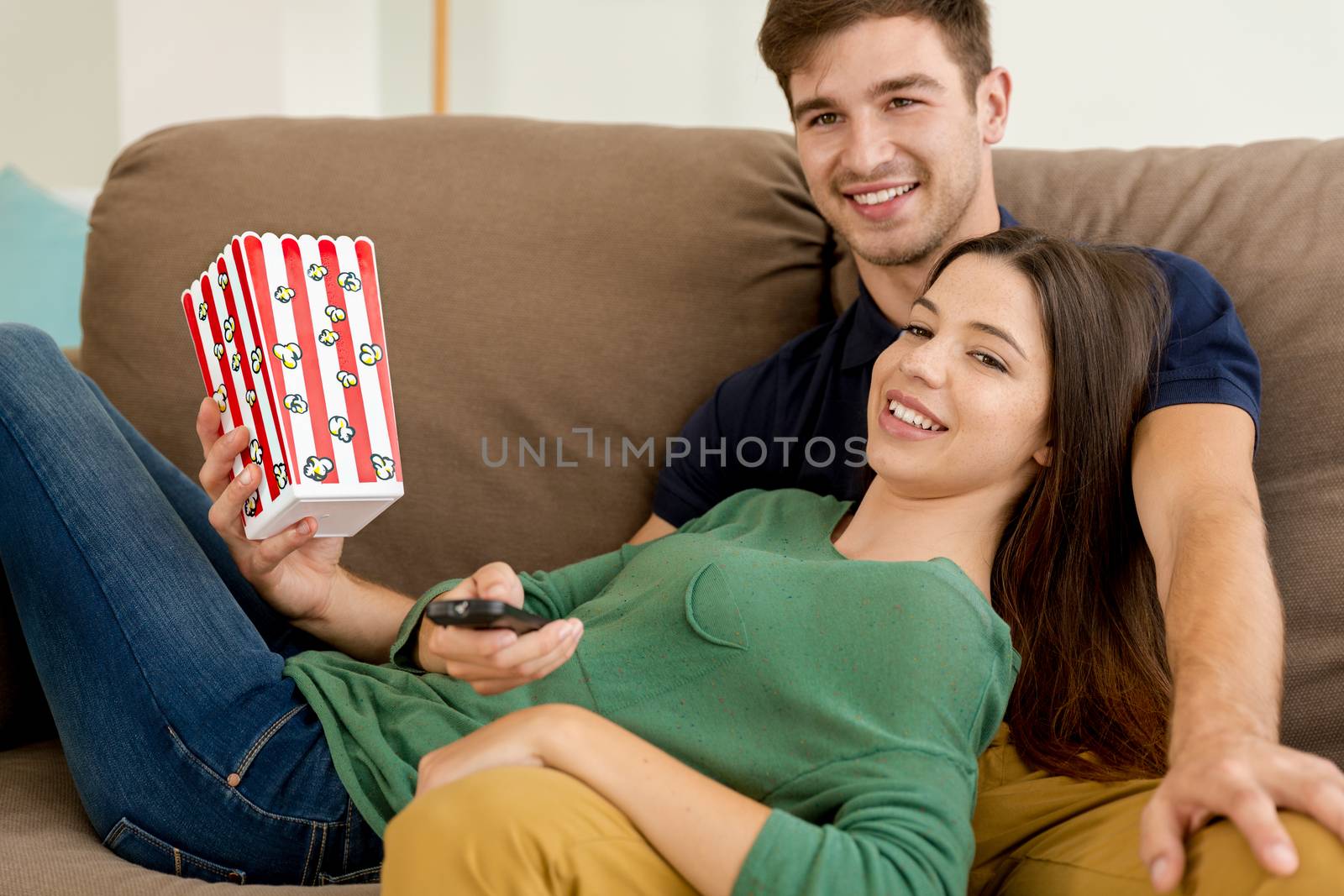 Young couple on the sofa and eating popcorns