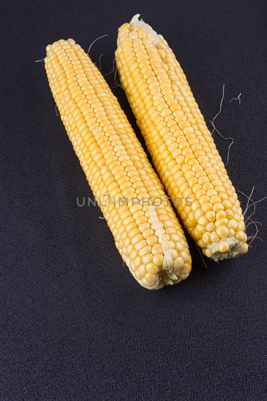 Raw corn on the black wooden board