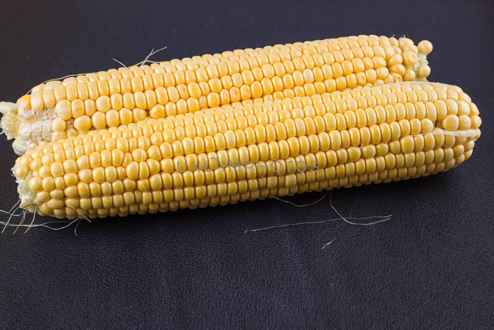 Raw corn on the black wooden board