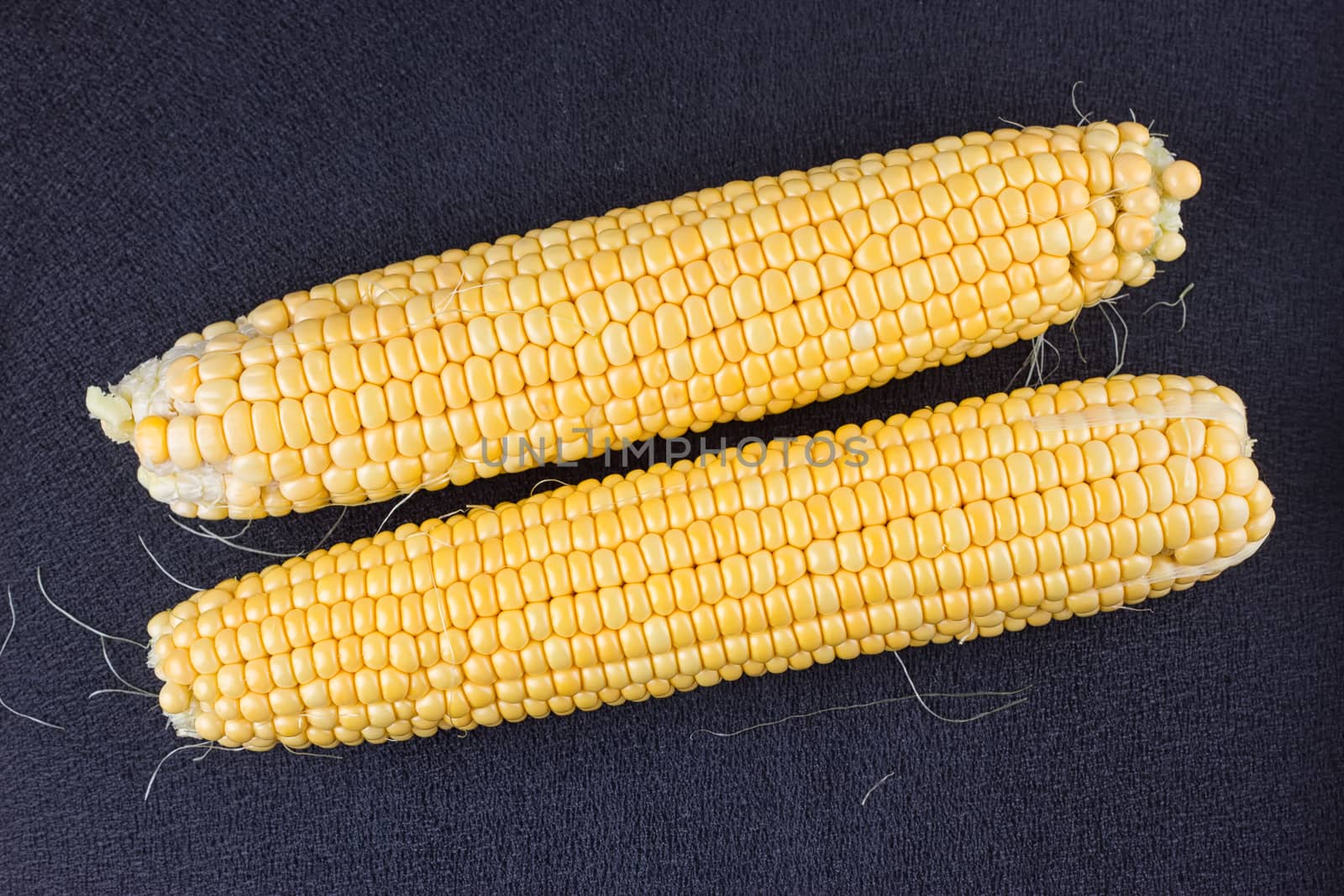 Raw corn on the black wooden board