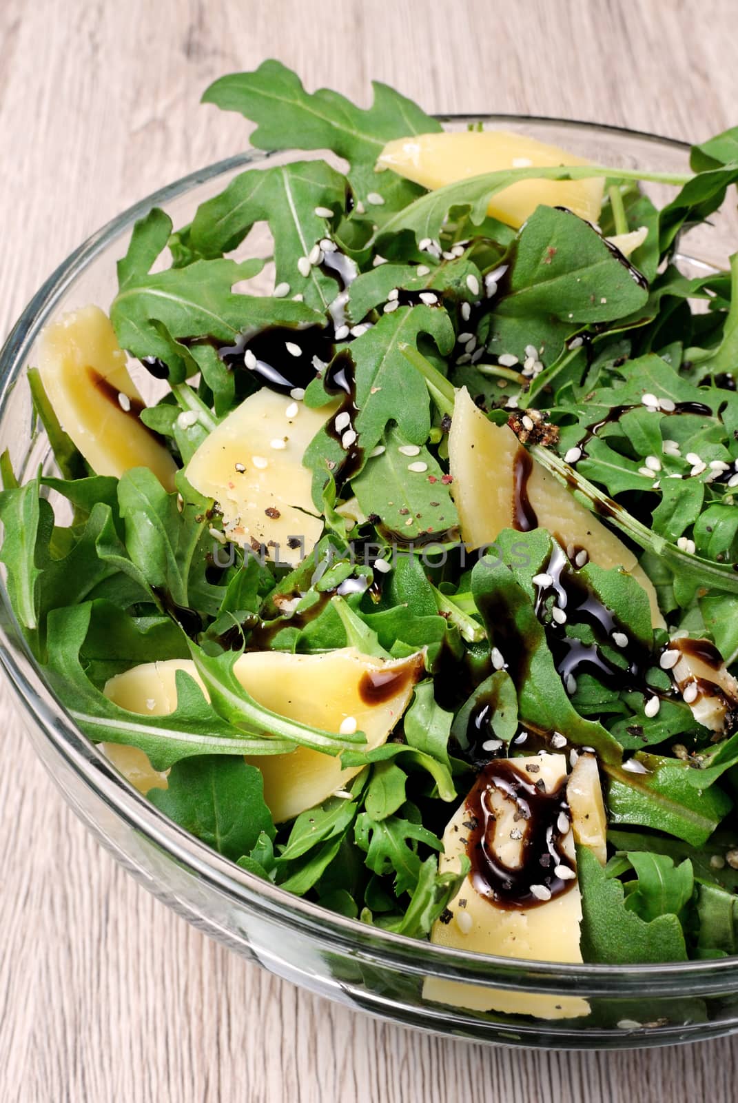 Arugula (rocket) salad dressed with balsamic soy sauce , Parmesan shavings and freshly ground black pepper, sesame.  