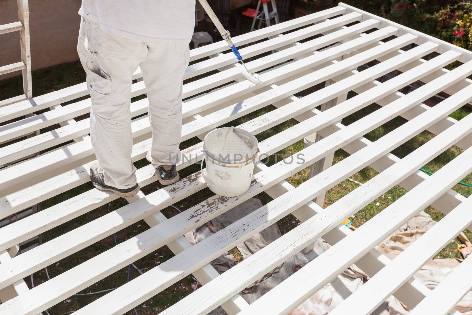 Professional Painter Rolling White Paint Onto The Top of A Home Patio Cover.