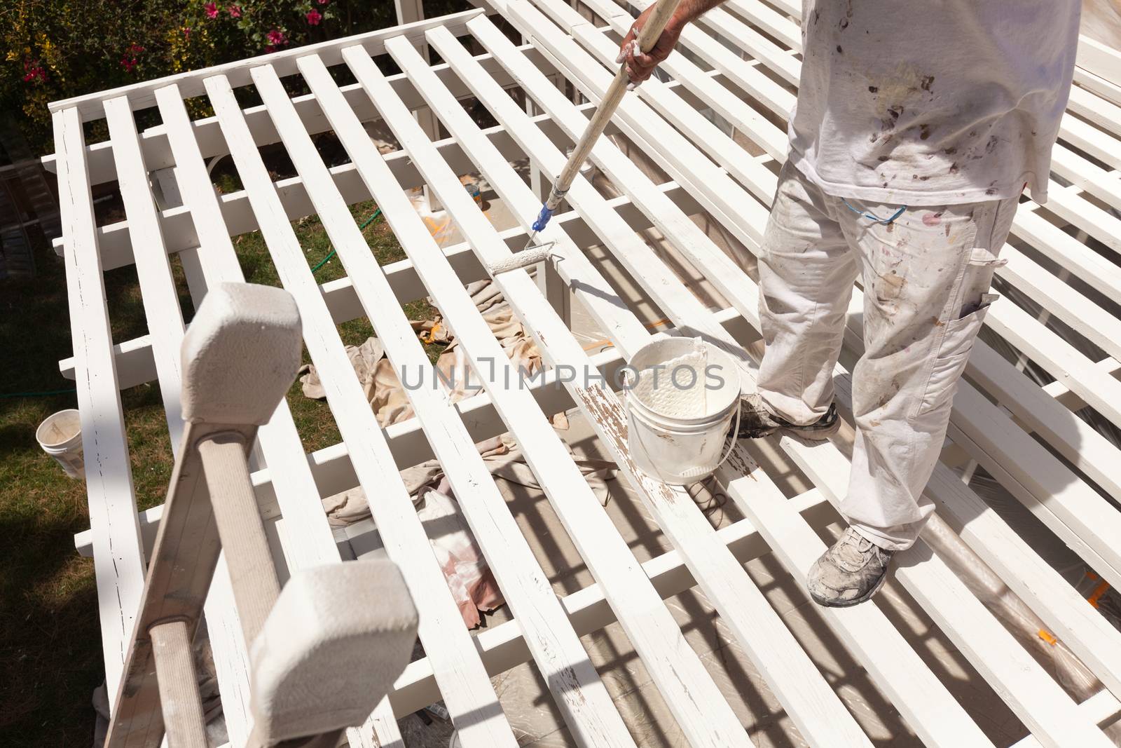 Professional Painter Rolling White Paint Onto The Top of A Home Patio Cover.