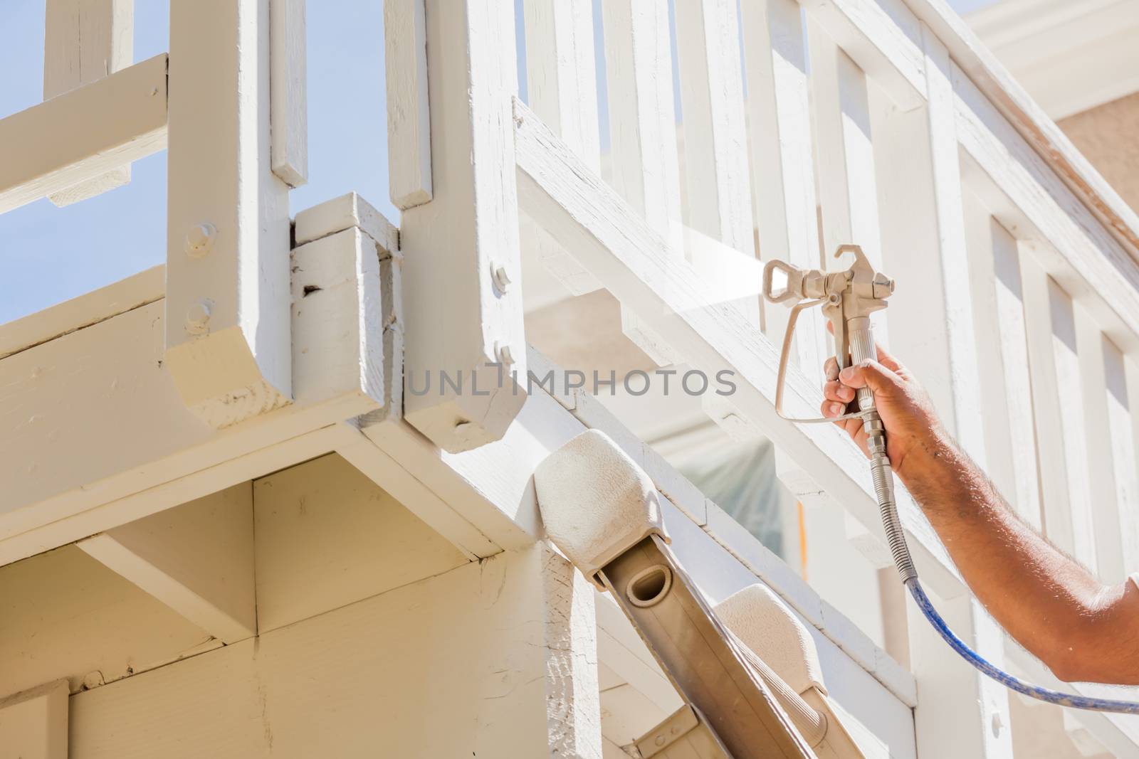 Professional House Painter Wearing Facial Protection Spray Painting Deck of A Home.