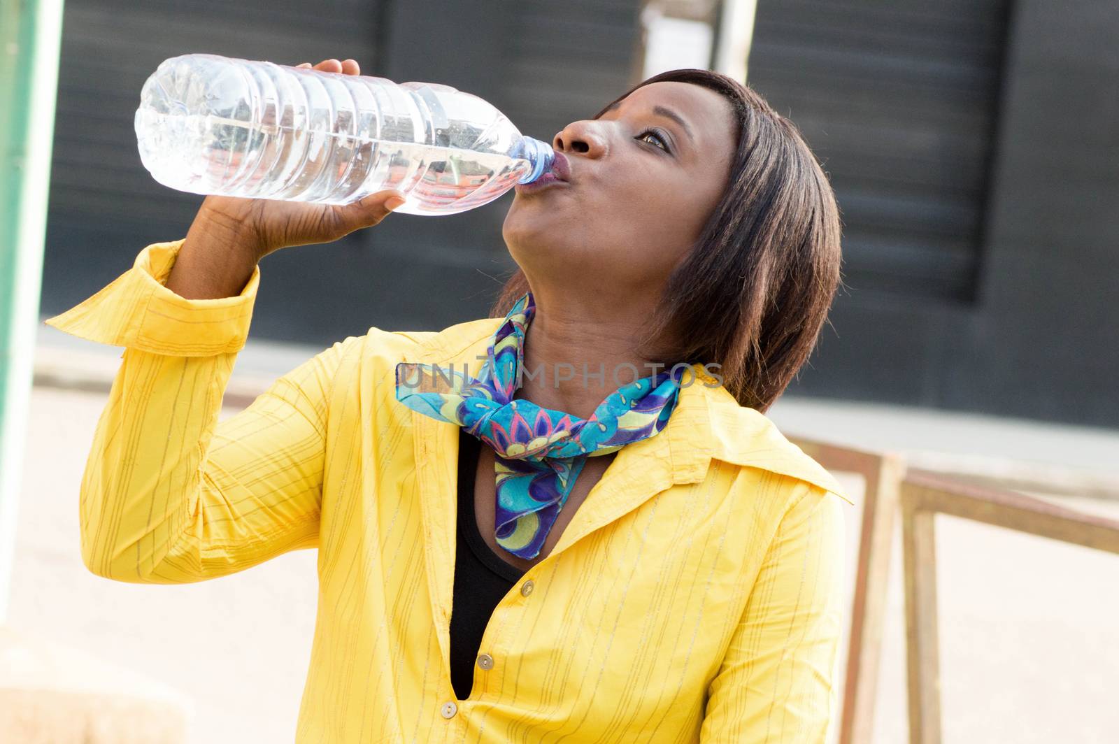 Portrait of a young woman sitting and drinking water in the bottle