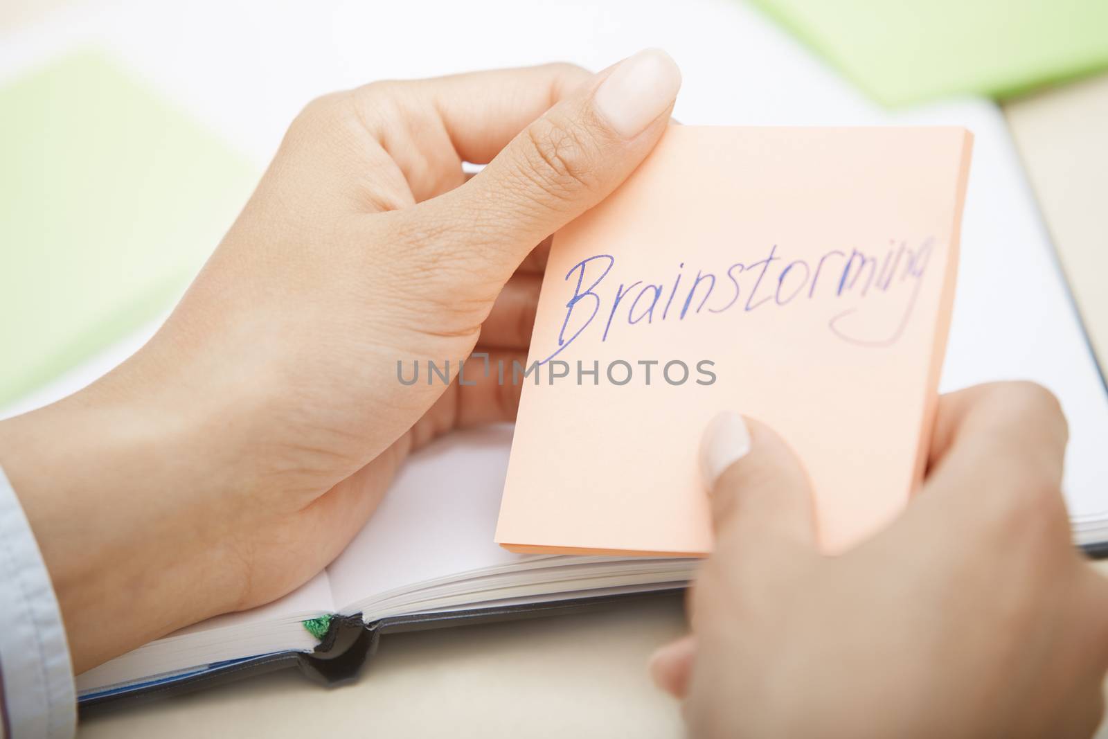 Hands holding sticky note with Brainstorming text