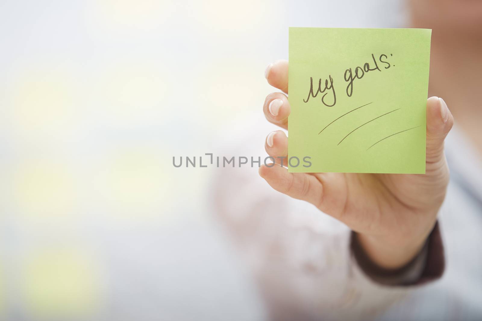 Woman holding sticky note with goals planning