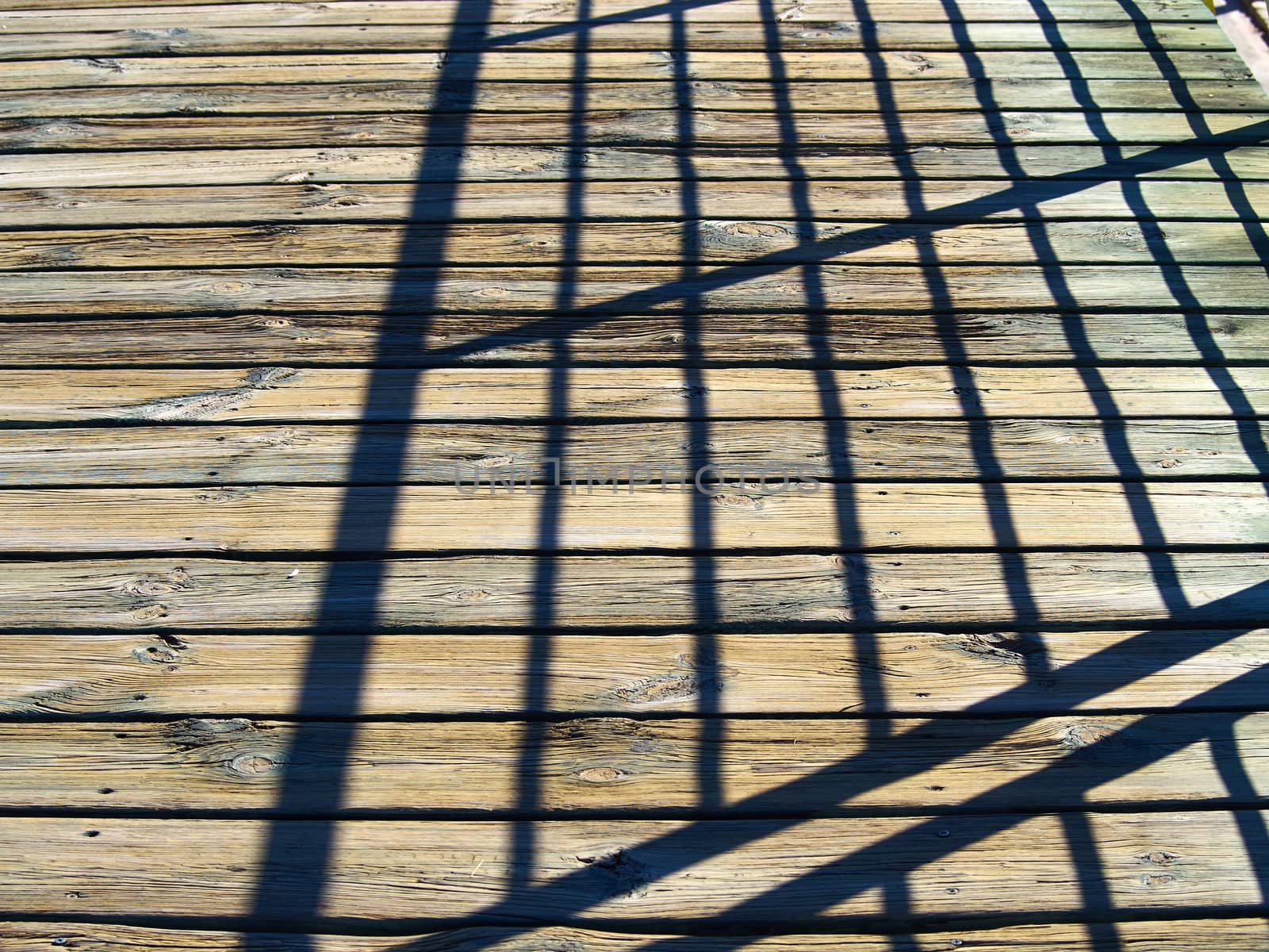 Abstract shadow of steel structure on wooden deck by Ronyzmbow