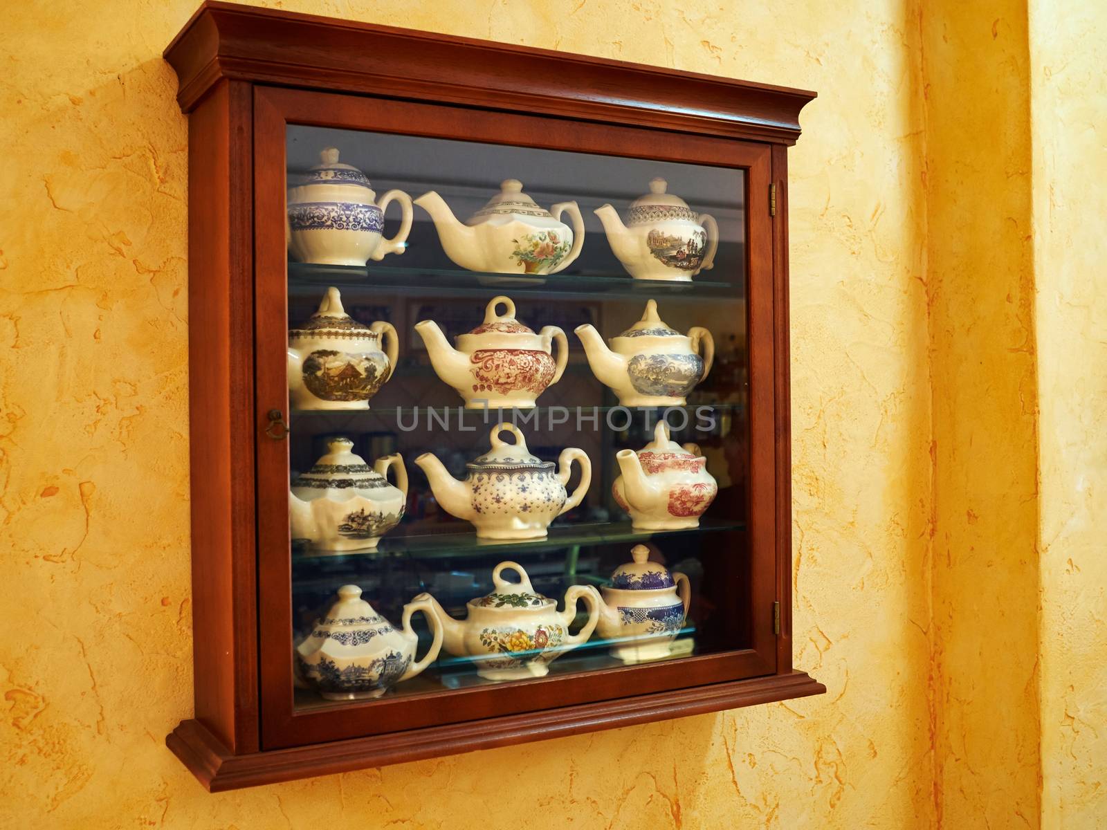 Collection of decorative classical design tea pot in a wooden display cabinet