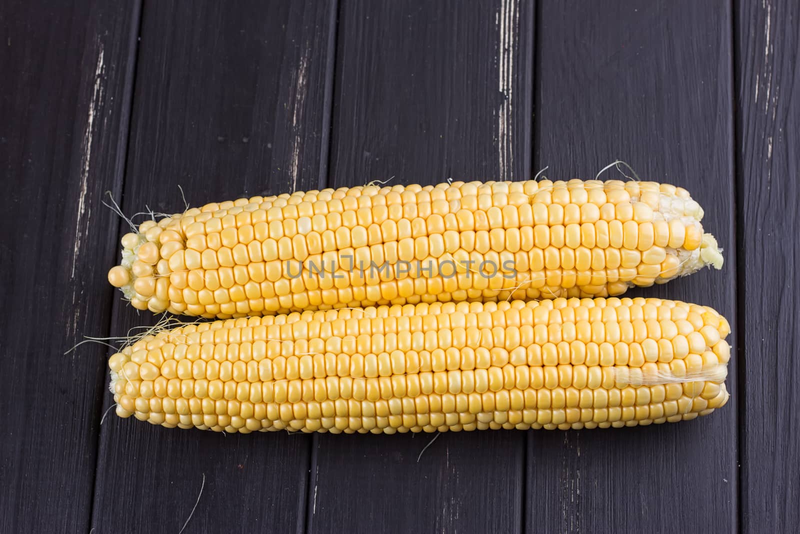 Raw corn on the black wooden board