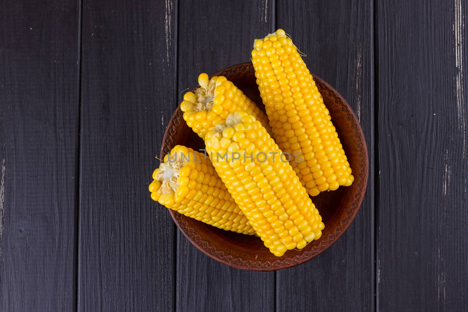 Boiled corn in a bowl on a black wooden background