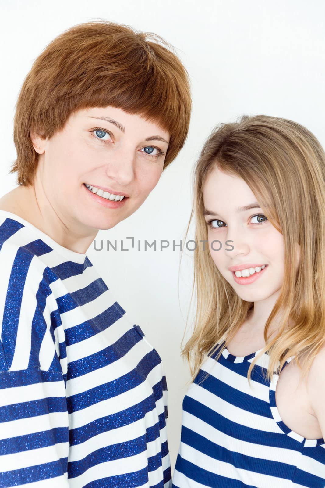 Portrait of happy mother and daughter near white wall