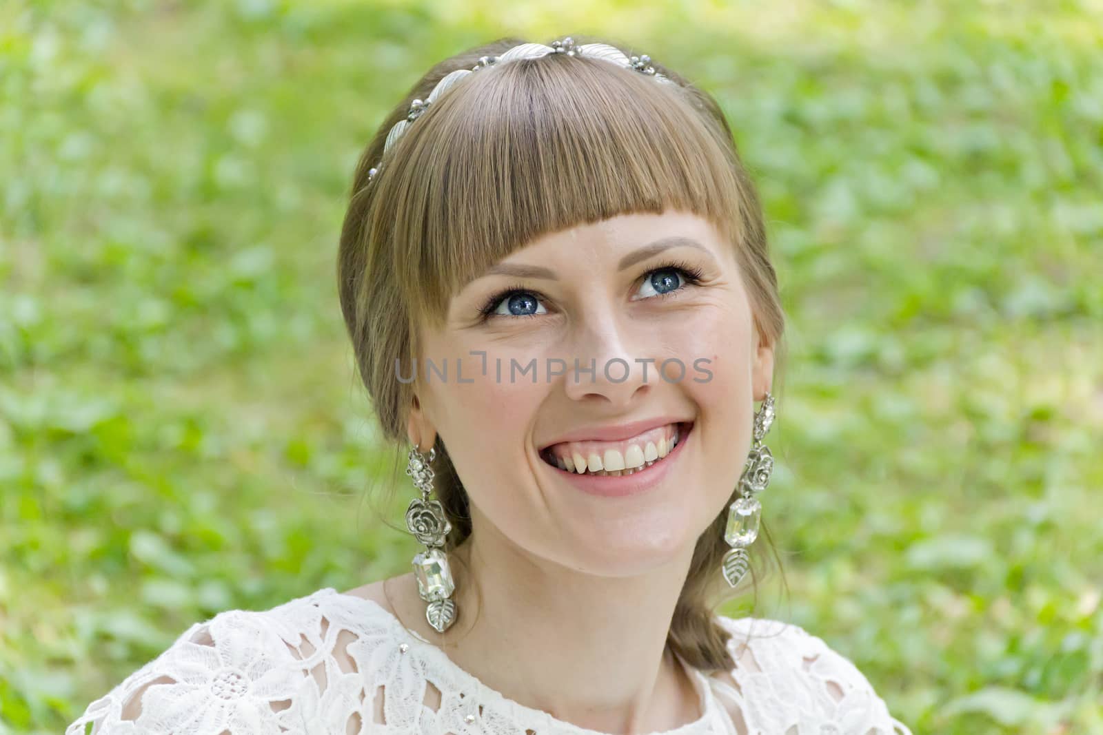 Beautiful smiling bride with diadem in the summer park