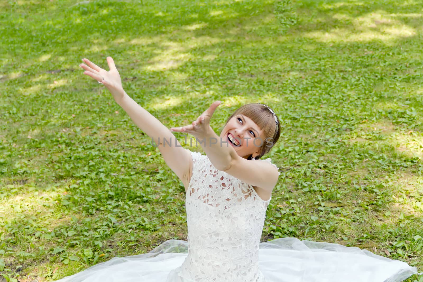 Beautiful bride in white lace dress with upwards hands