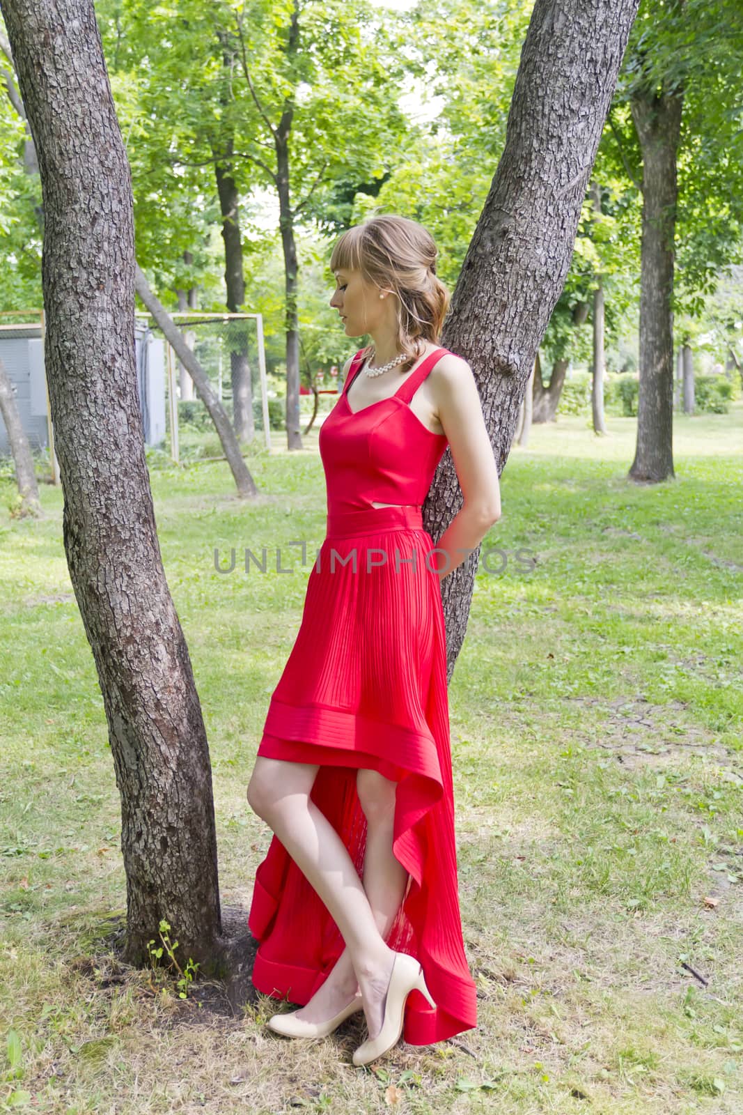 Beautiful lady in red are standing near tree summer day