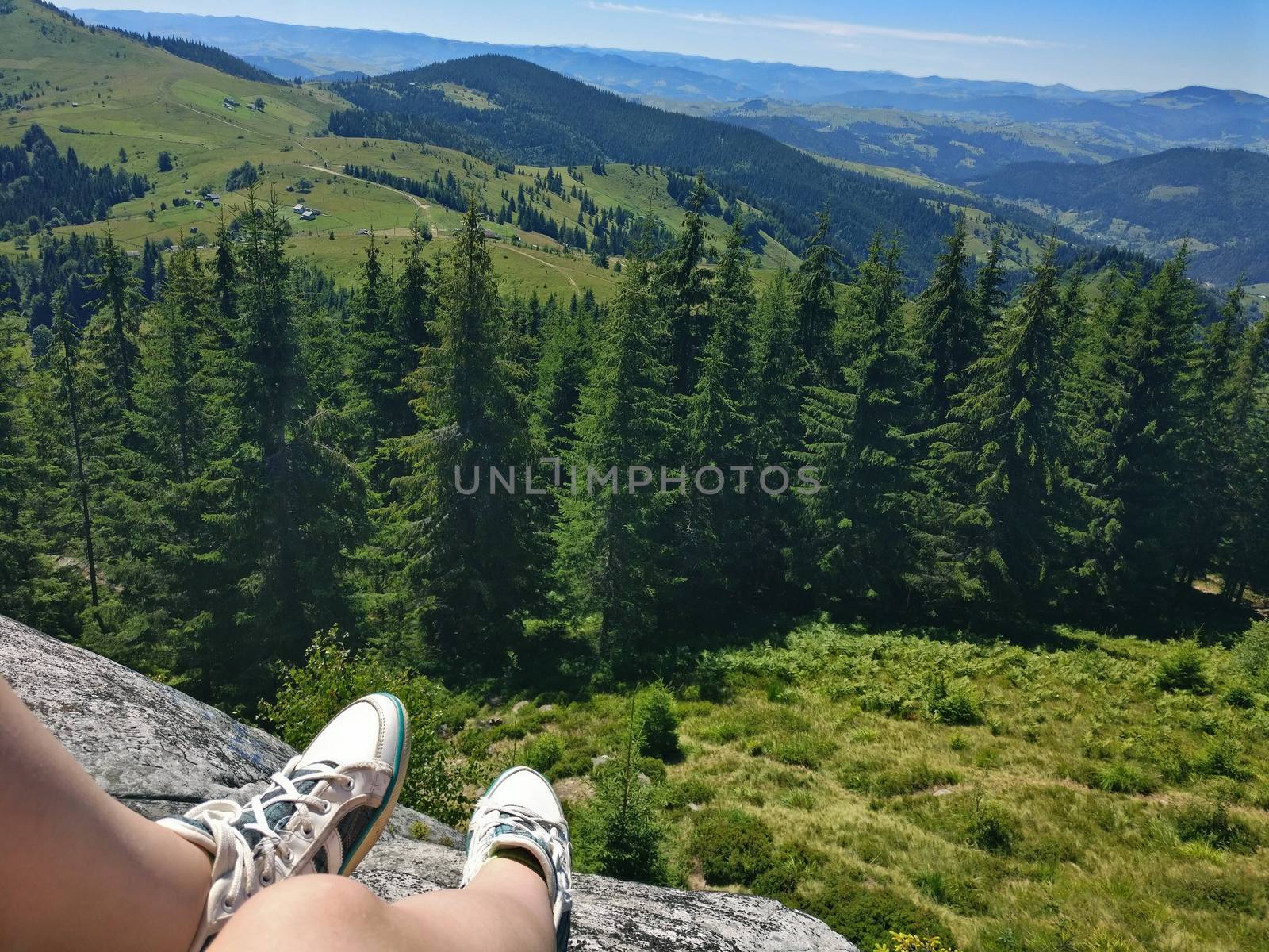 Legs of traveler sitting on a high mountain top in travel. Freedom concept