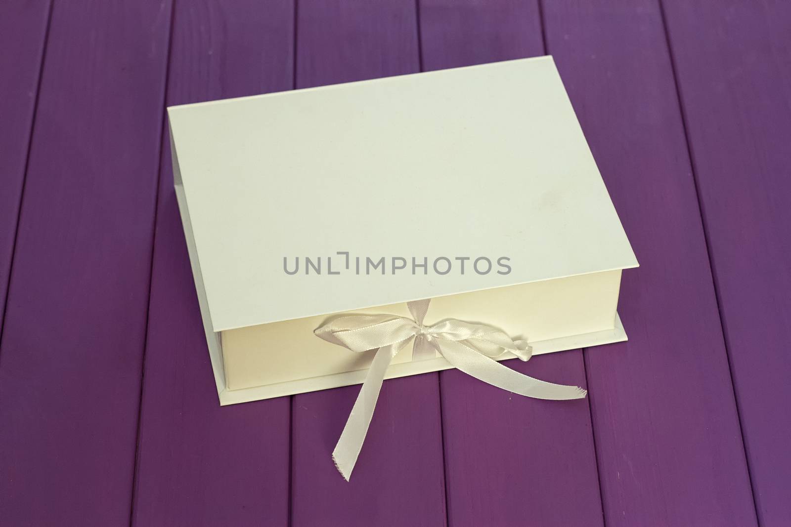 White box on the tie on a purple wooden background. Mocap