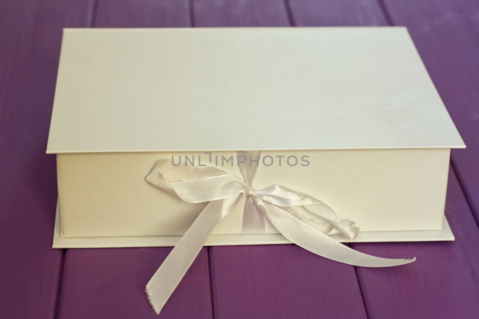 White box on the tie on a purple wooden background. Mocap