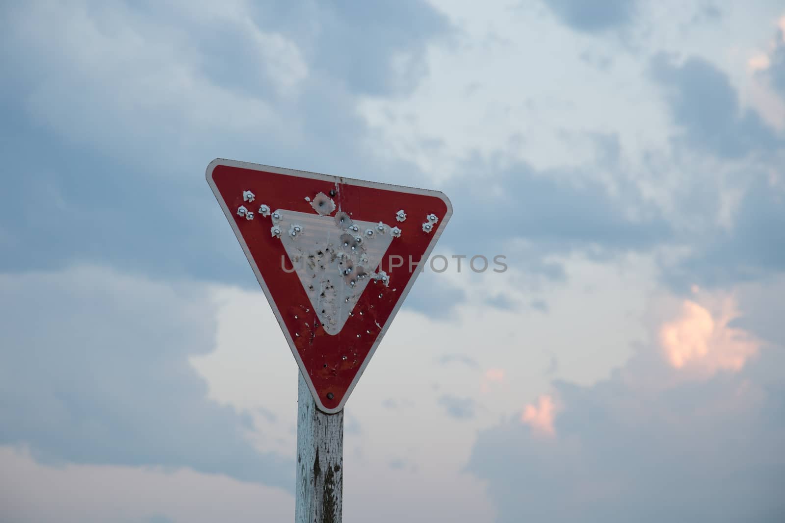 An old yield sign that has been shot multiple times.
