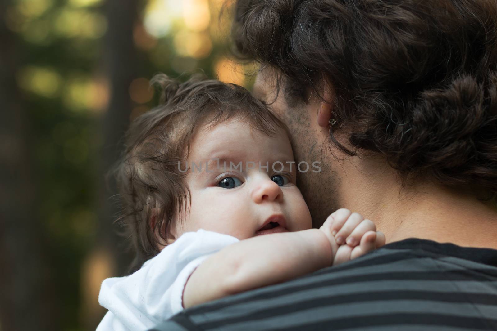 Close up of young father holding his newborn baby. Focus on the baby's blue eyes.