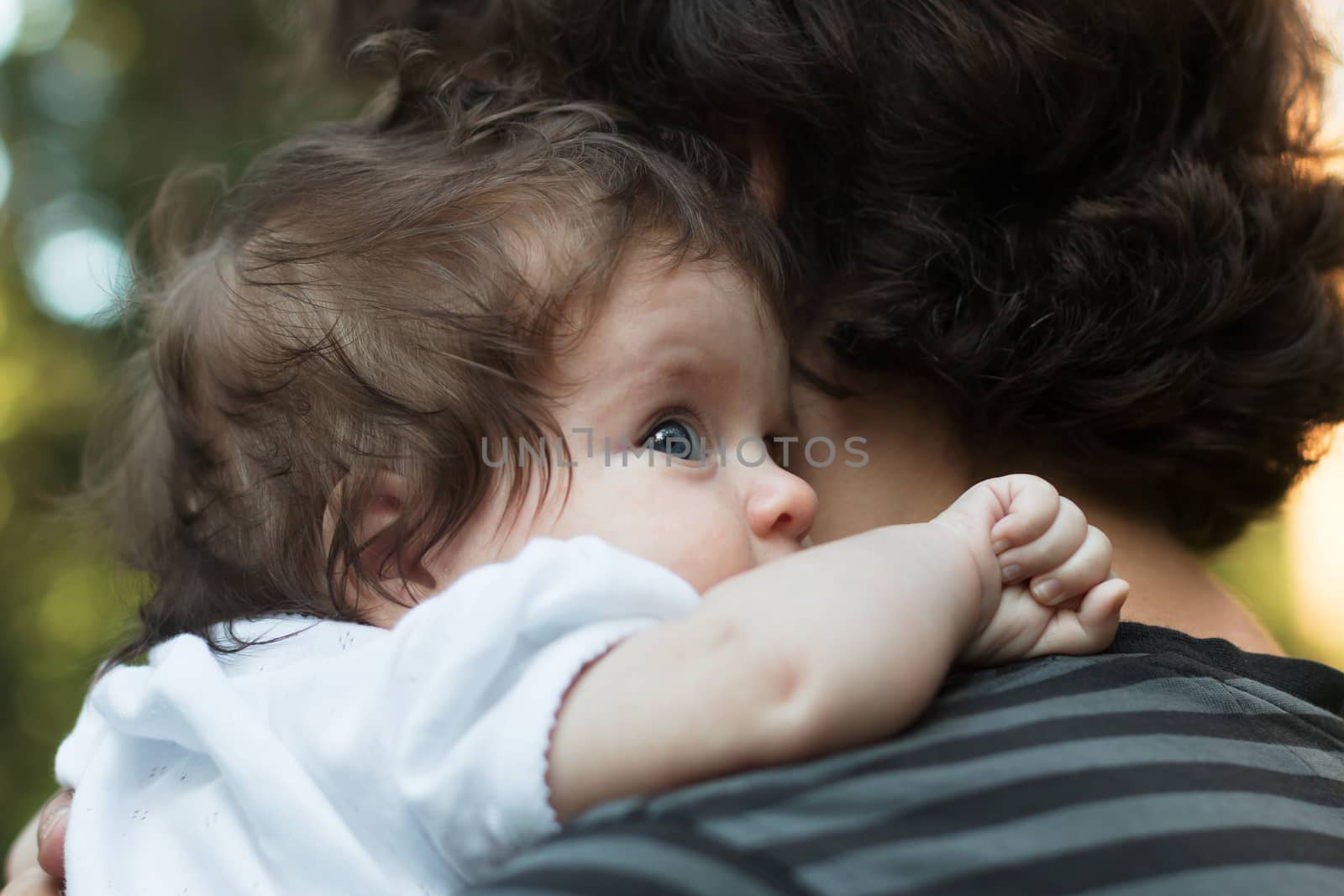 Little Girl resting on her father's shoulder. Happy sweet girl hugging her father on the forest background.