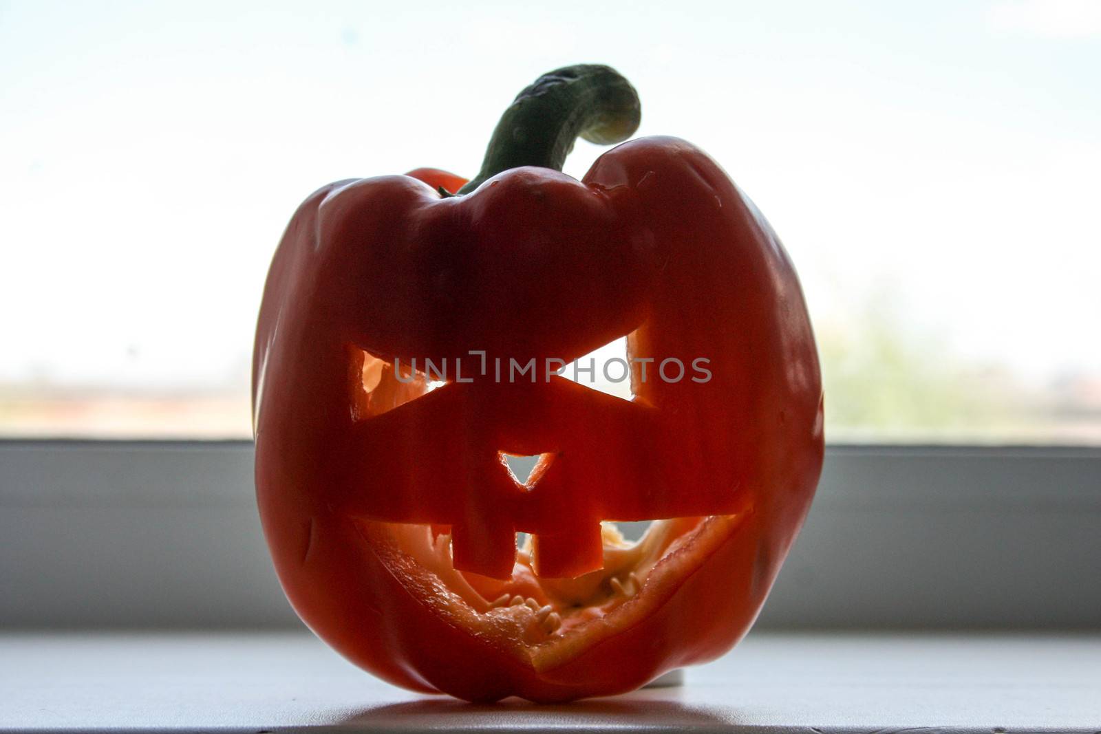 Halloween concept. Pumpkin smiling on a light window. Mask with an ugly face. Photo for your design