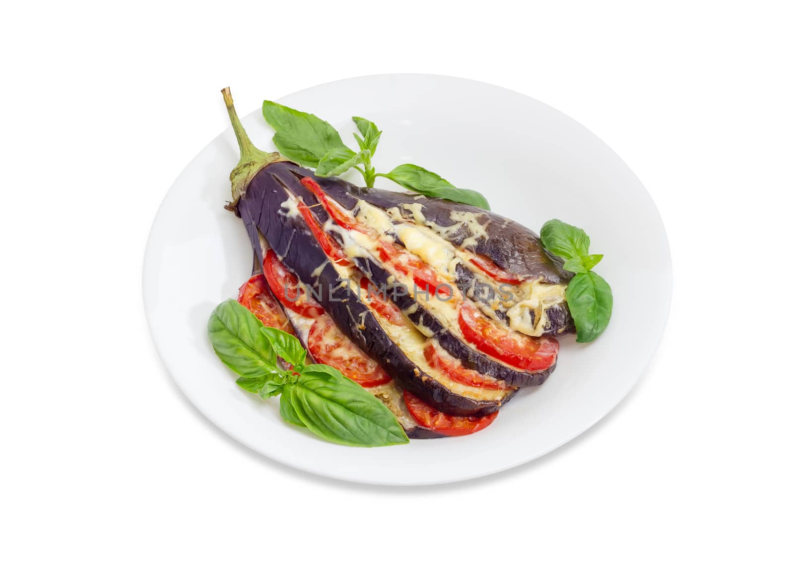 Baked eggplant stuffed with vegetables and cheese decorated with basil leaves on white dish on a white background
