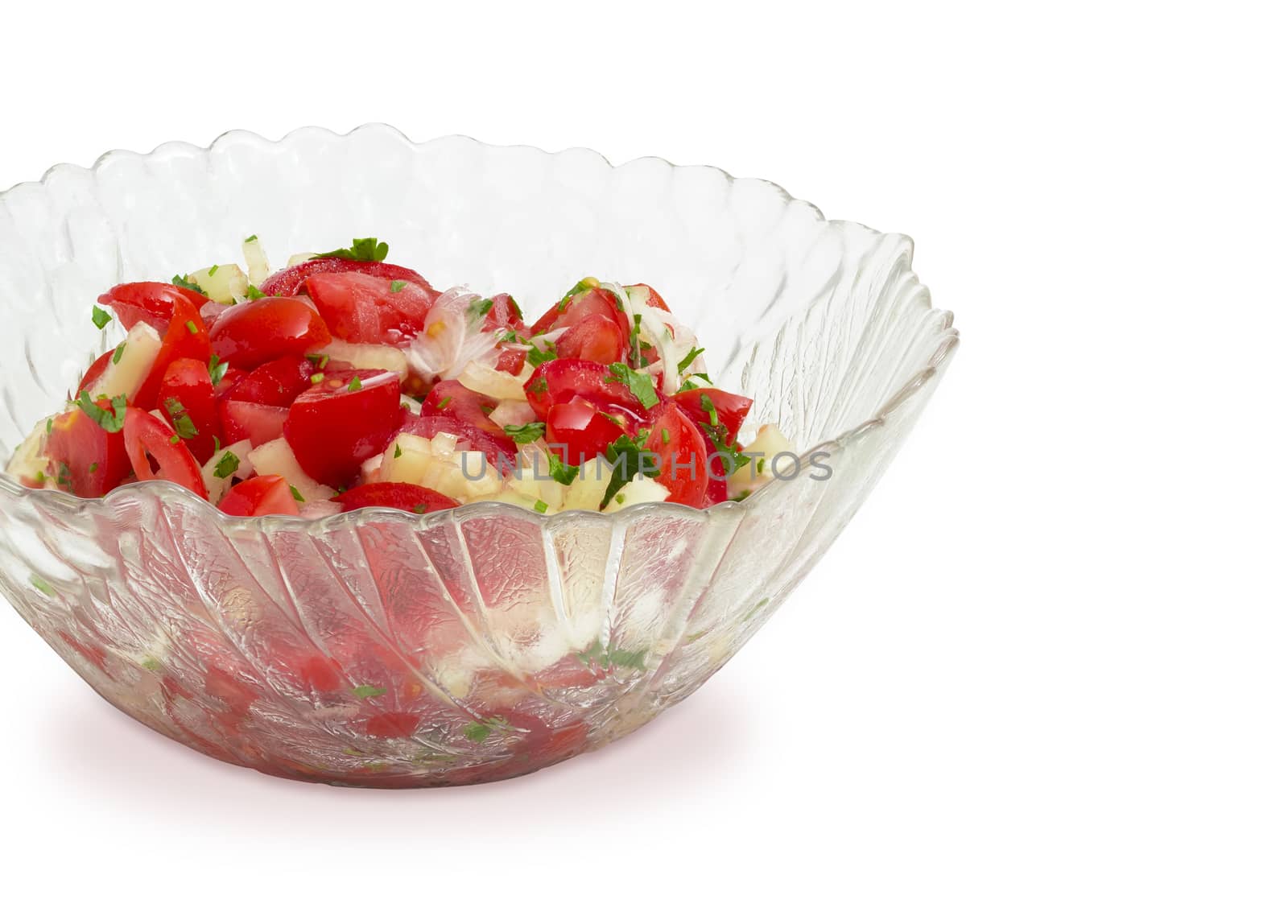 Fragment of the glass salad bowl with vegetable salad of a fresh sliced tomatoes, white bell pepper, onion and greens on a white background
