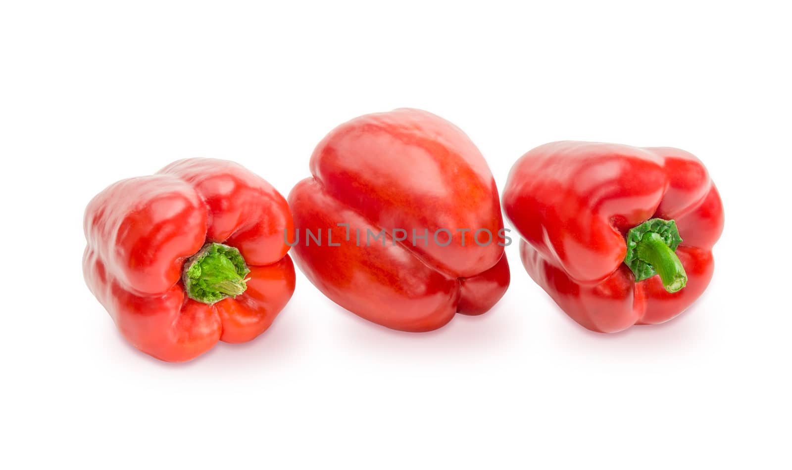 Three fresh red bell peppers on a white background closeup
