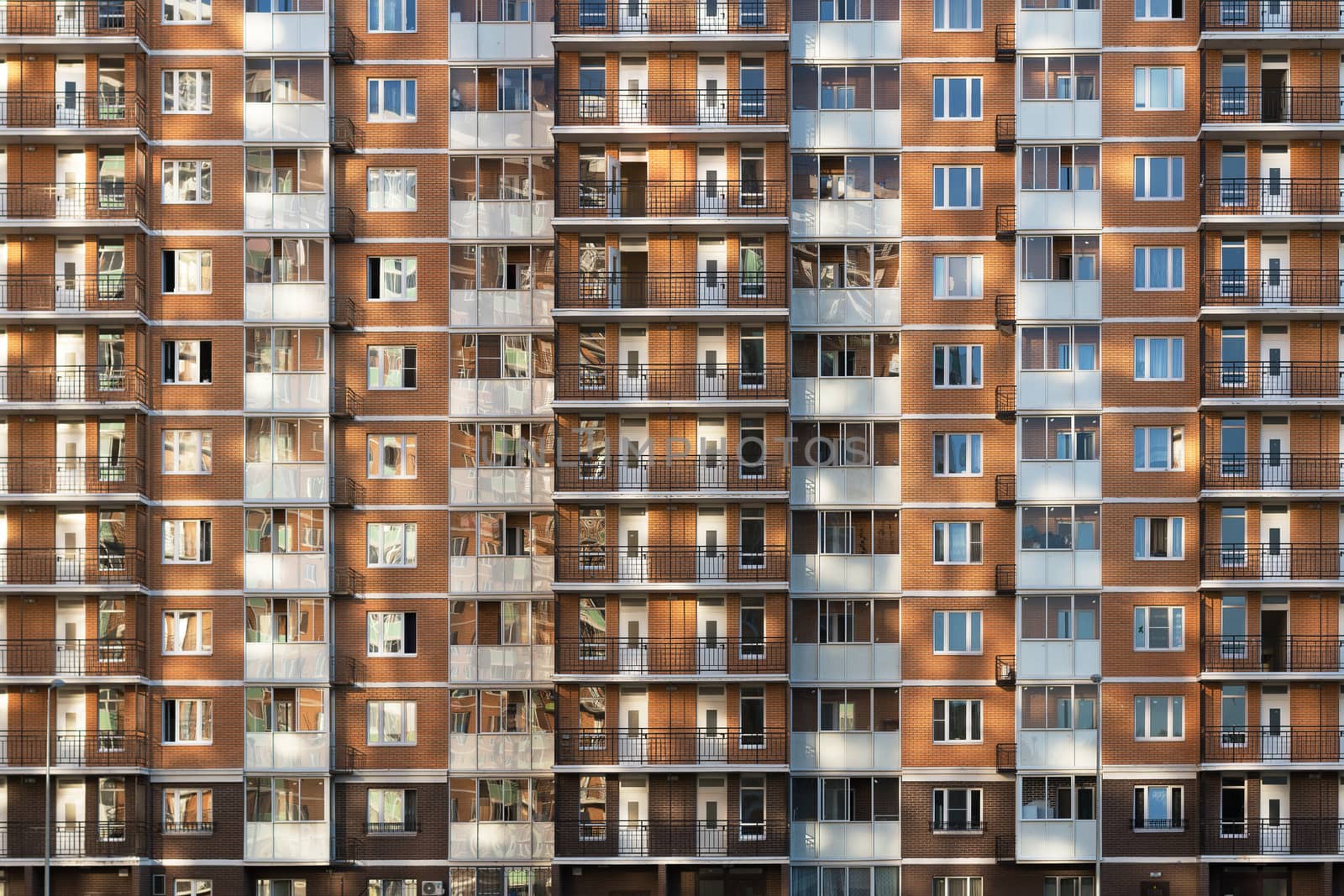 Fragment of one of the serial high-rise apartment buildings in Moscow suburbs with the sunset glare on the wall and windows. New building construction.