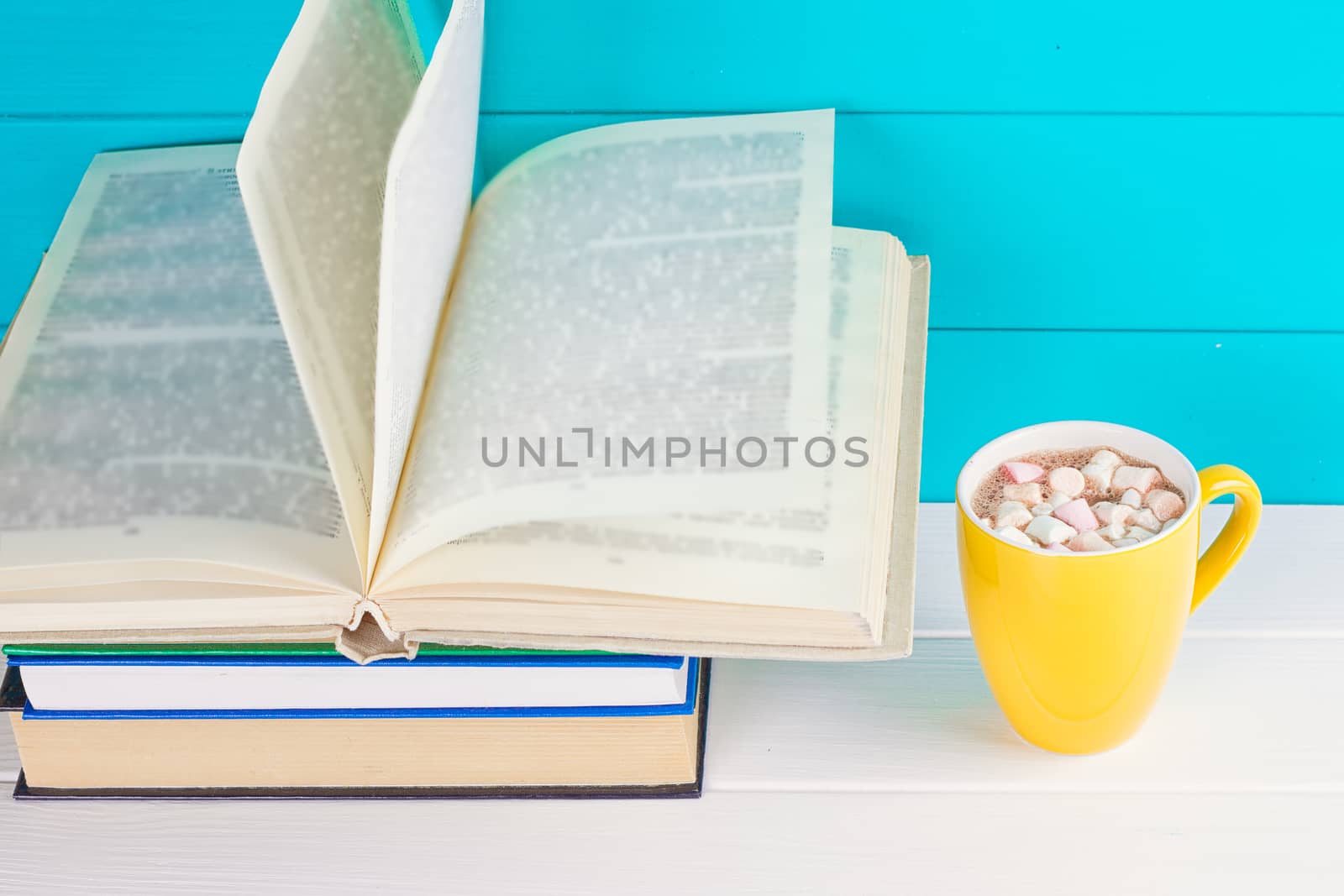 Stack of books on wooden table with a cup of tea by victosha