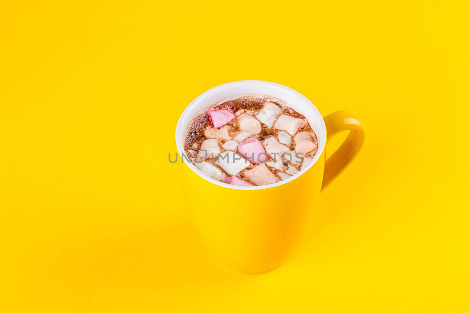 Yellow cup of hot cocoa with marshmallows on yellow background