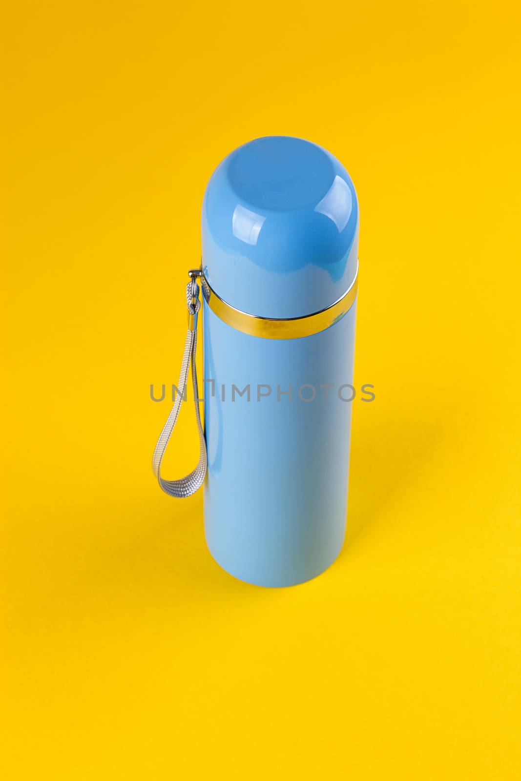 Blue thermos for hot drinks on a yellow background