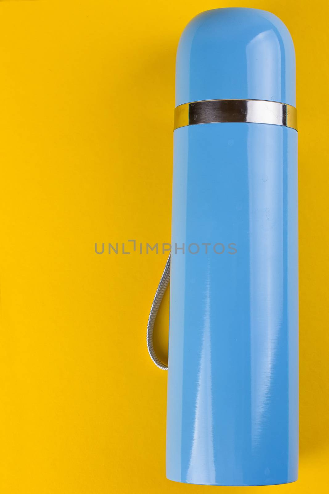 Blue thermos for hot drinks on a yellow background