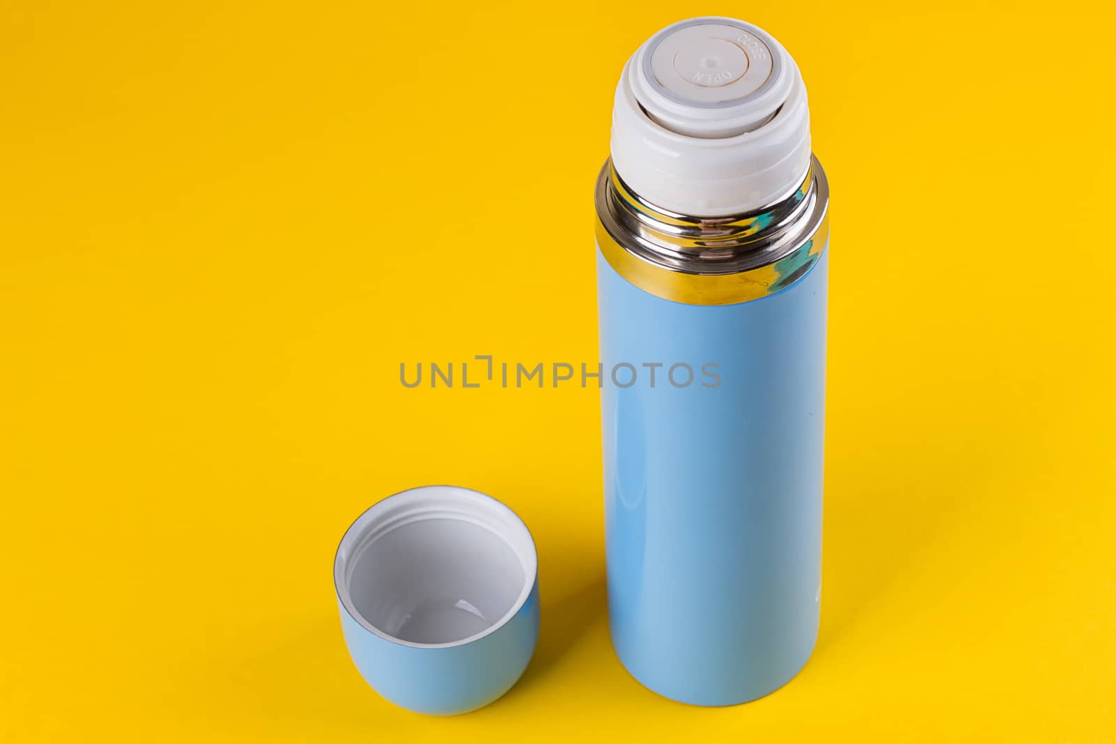 Blue thermos for hot drinks on a yellow background