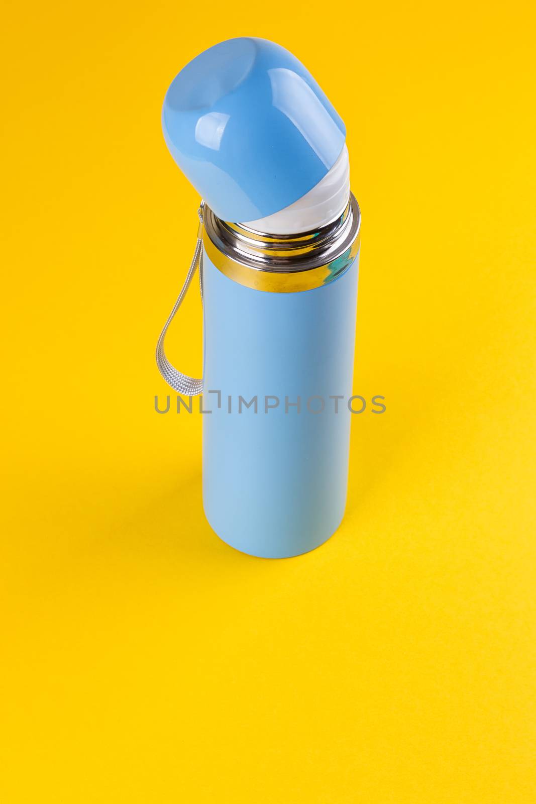 Blue thermos for hot drinks on a yellow background