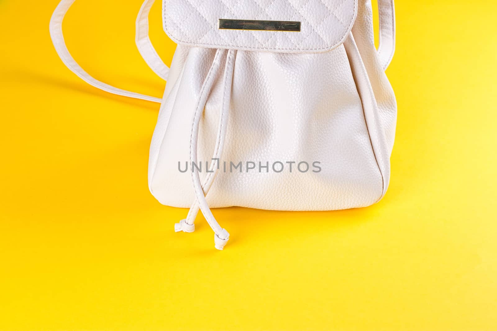 The female white leather backpack on a yellow background