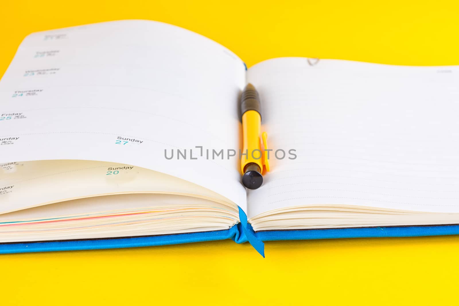 Open diary and pen on a yellow background