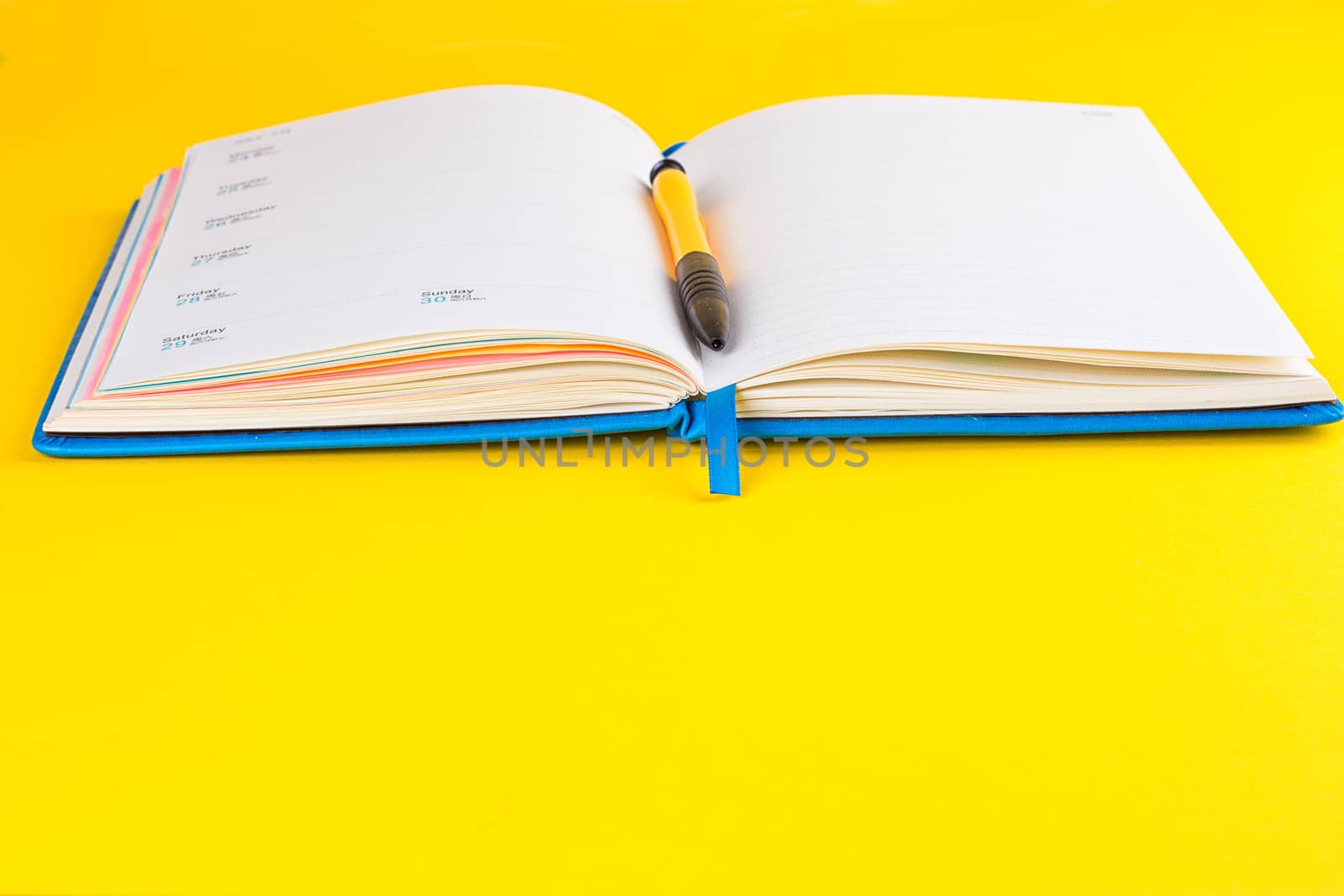 Open diary and pen on a yellow background