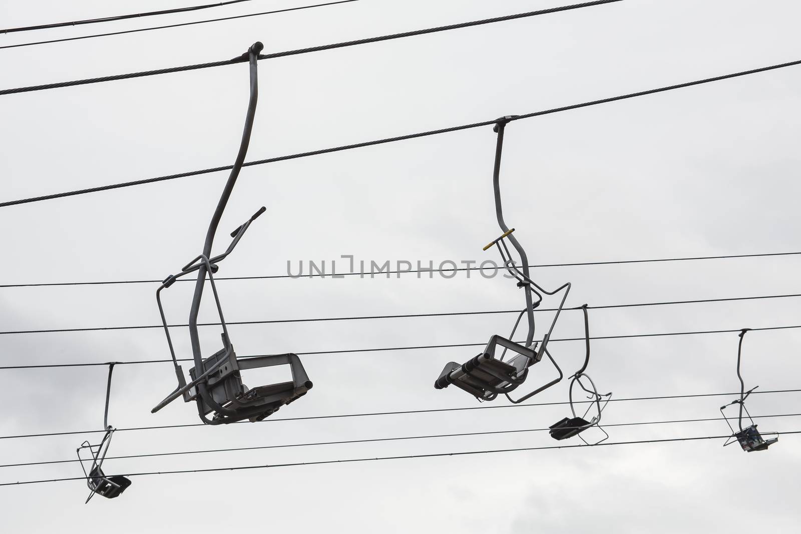 Empty chairlift with cloudy sky in the background. Cableway chairlift