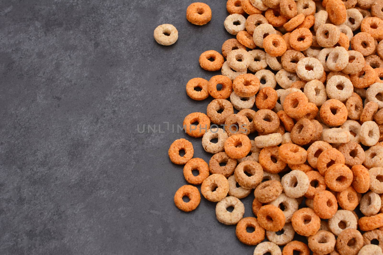 Multigrain hoops breakfast cereal in a border line with copy space on a dark grey slate tile background