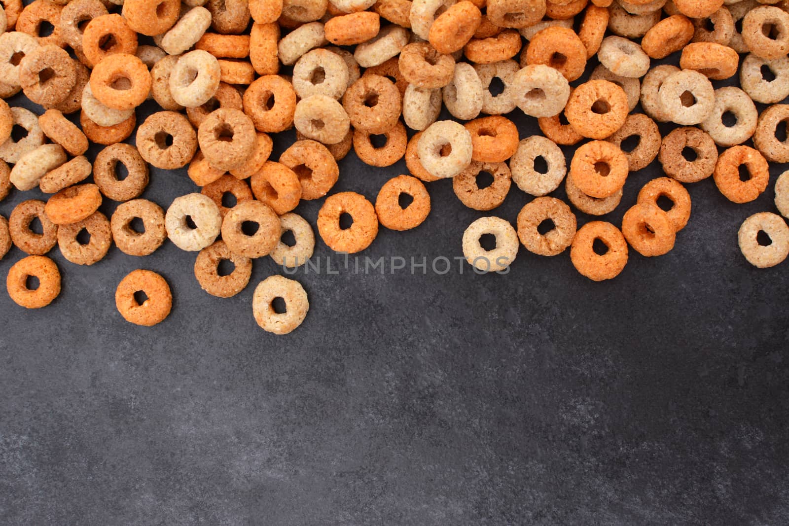 Multigrain hoops breakfast cereal border with copy space on a dark grey slate tile background